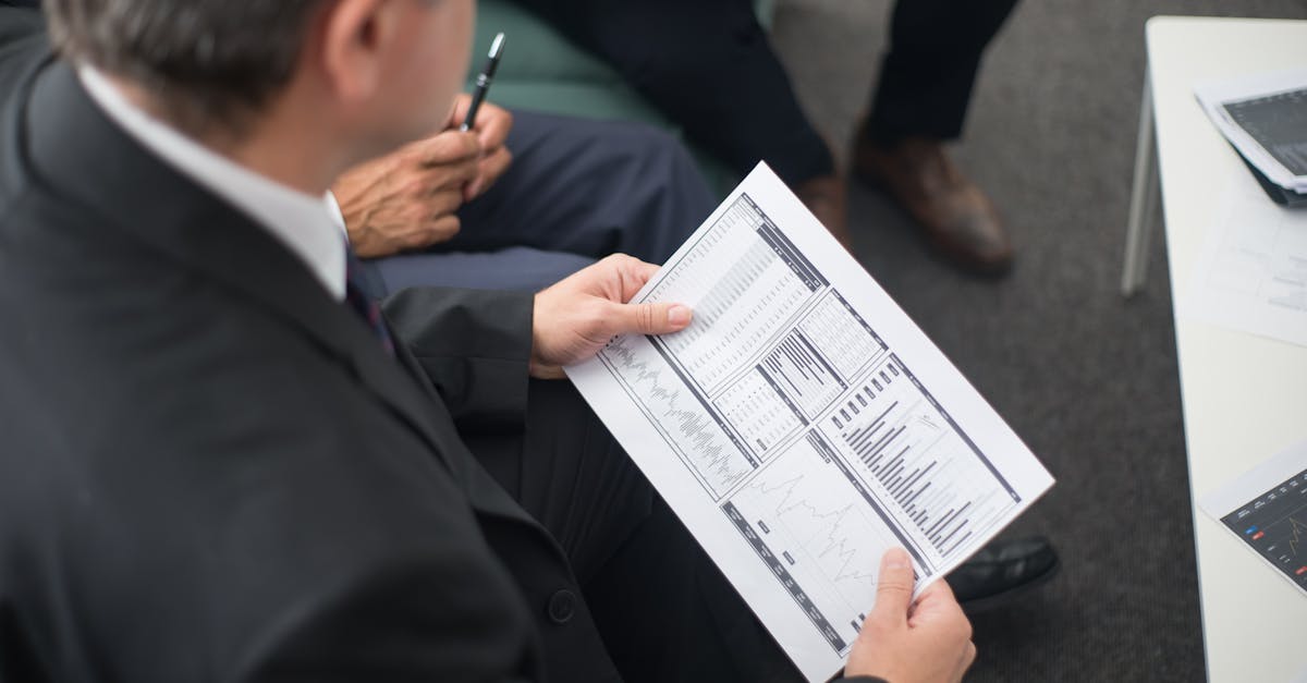 Two businessmen analyze financial documents during a meeting, focusing on data trends and performance.