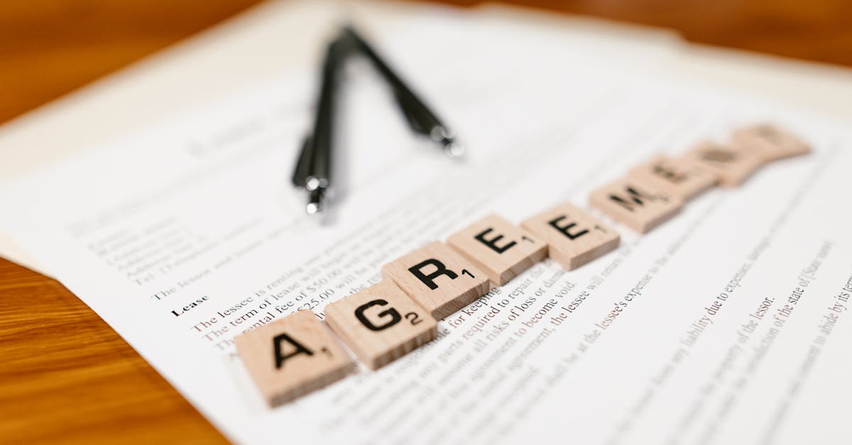 Scrabble tiles spelling 'AGREEMENT' on a lease document, emphasizing contractual themes.