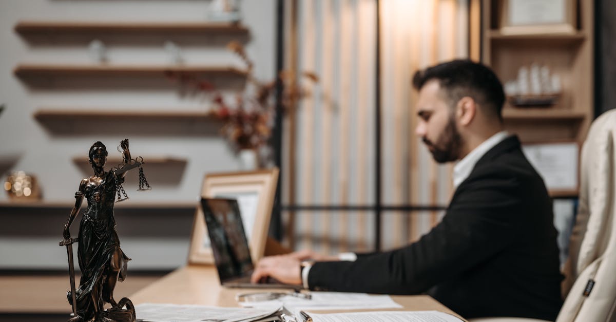 Lawyer working diligently on a laptop in a modern office, Lady Justice statute present.