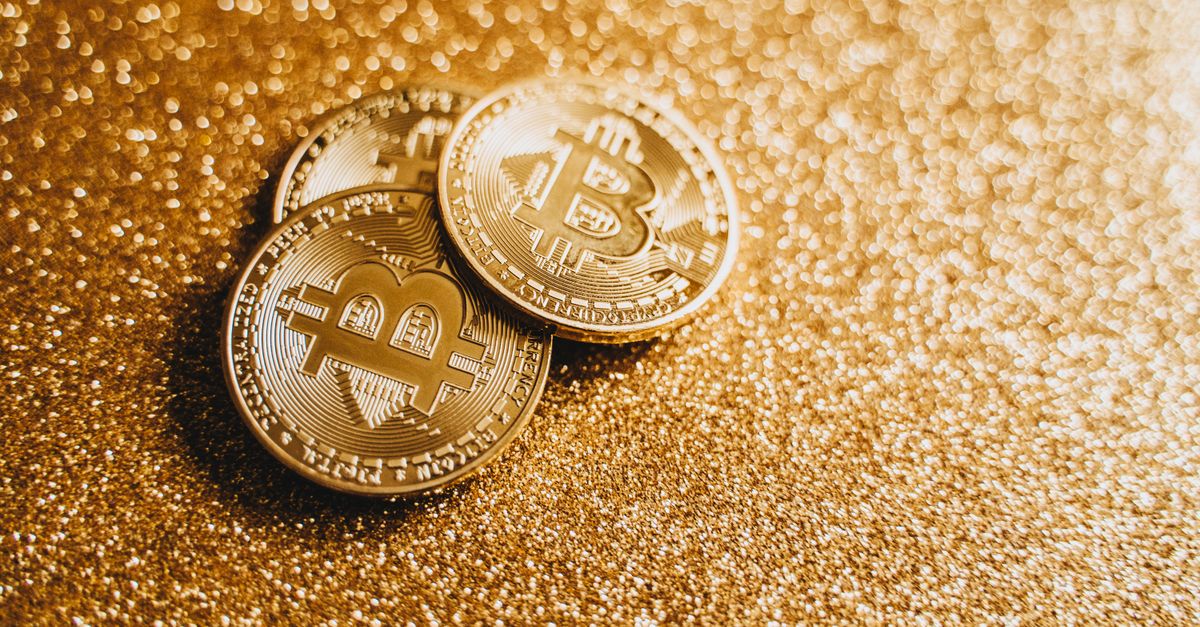 Closeup of three Bitcoin coins on a shimmering gold glitter background, symbolizing digital wealth.