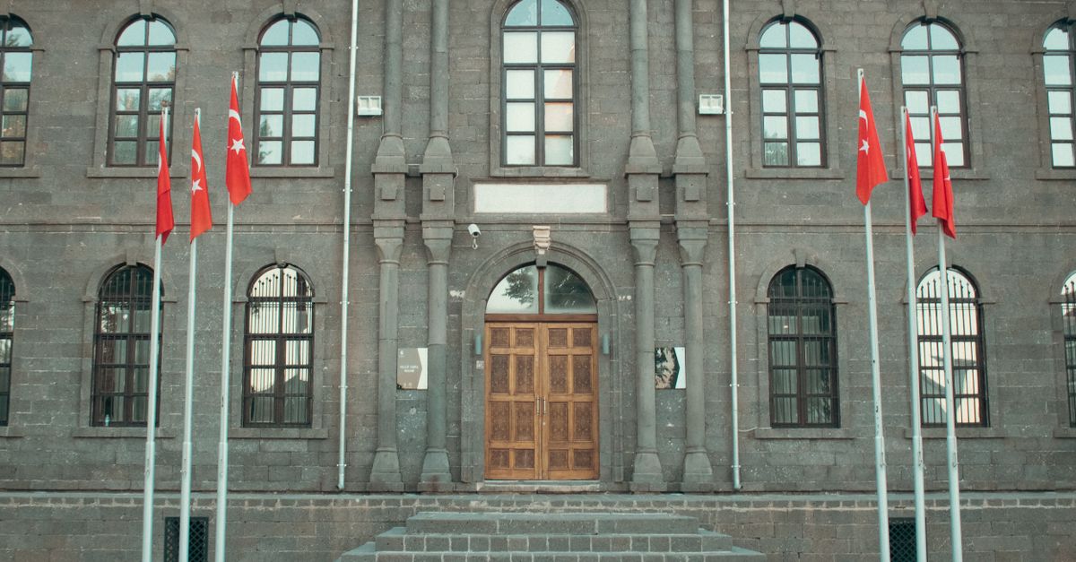Front view of a historic stone museum with Turkish flags in Diyarbakır, Turkey.
