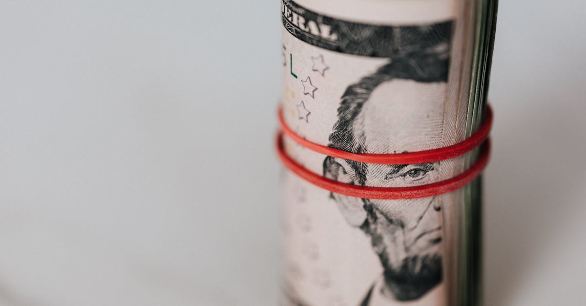 Close-up of a roll of US dollars wrapped with a red rubber band focusing on financial abundance.