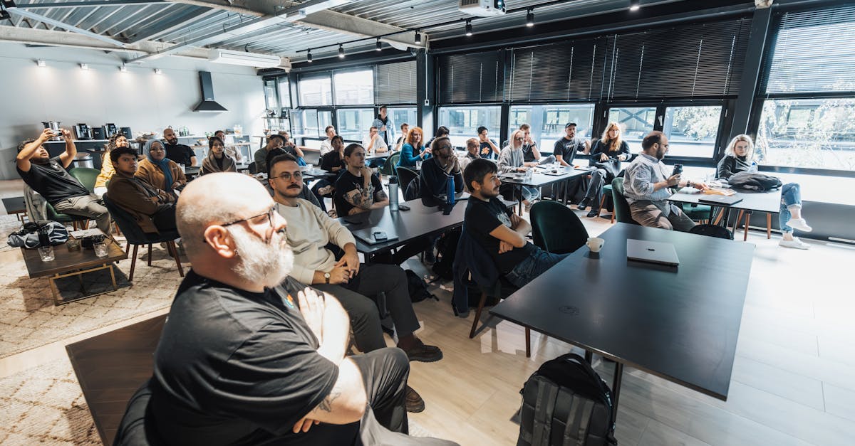 A diverse group of professionals attentively listening during an indoor business meeting in a modern conference room.