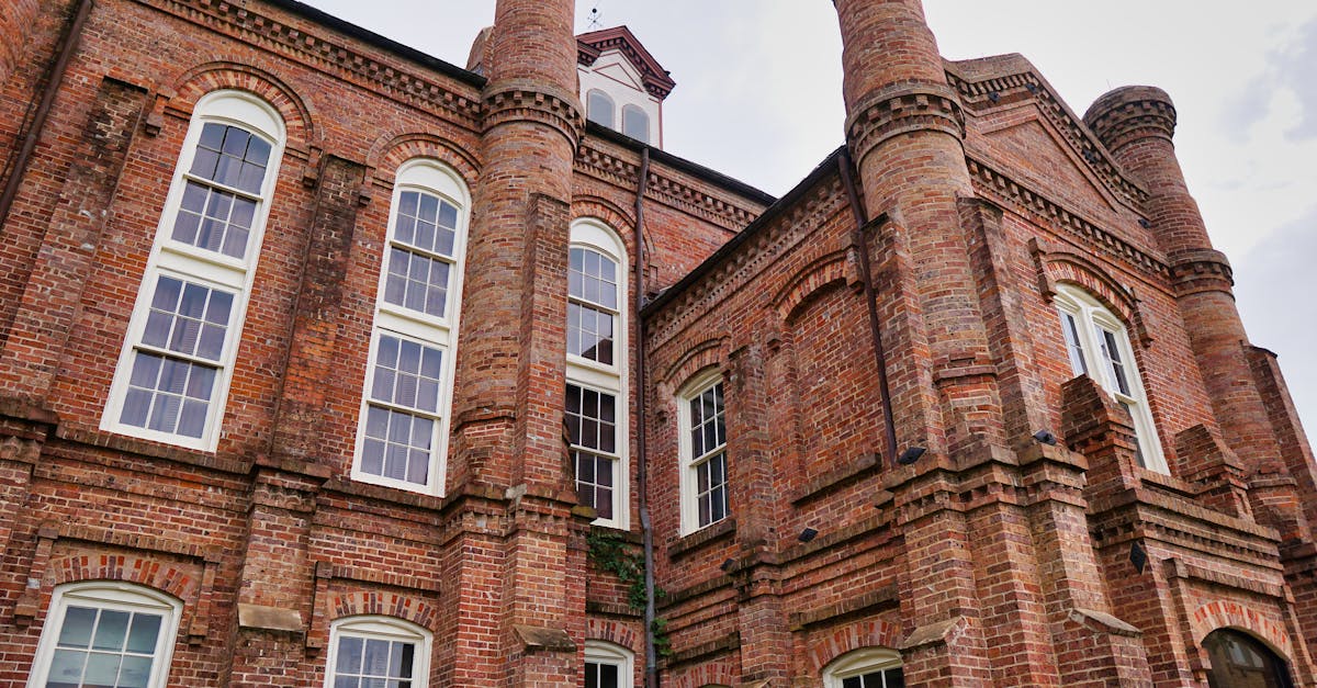 Low-angle shot of a historical brick courthouse featuring arched windows and architectural details.