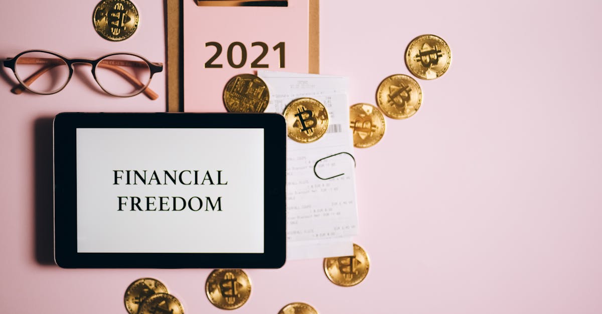 Flat lay image of financial freedom concept with bitcoins, tablet, and clipboard on a pink background.