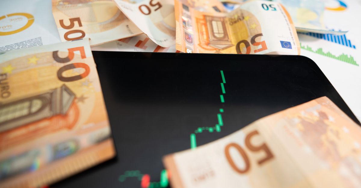 Close-up of 50 euro banknotes with a digital stock market chart on a tablet, depicting financial growth.