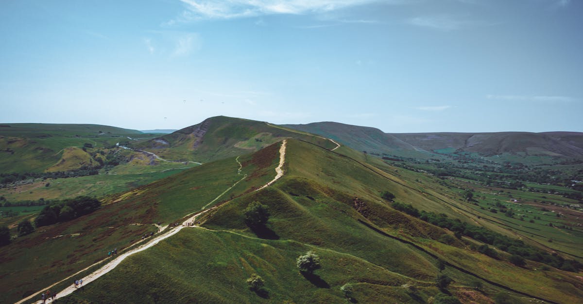 A stunning aerial capture of rolling hills with a scenic hiking trail under a clear blue sky.