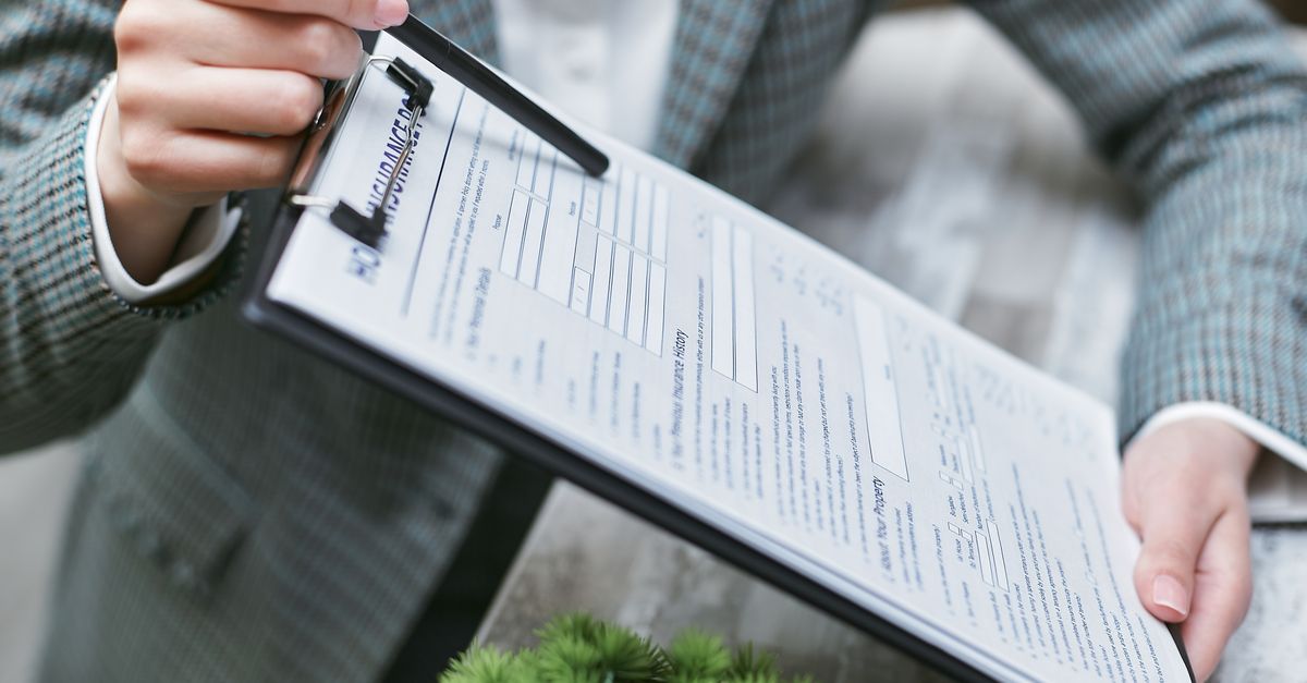 Close-up of a businessperson holding a clipboard with an insurance document, emphasizing details.