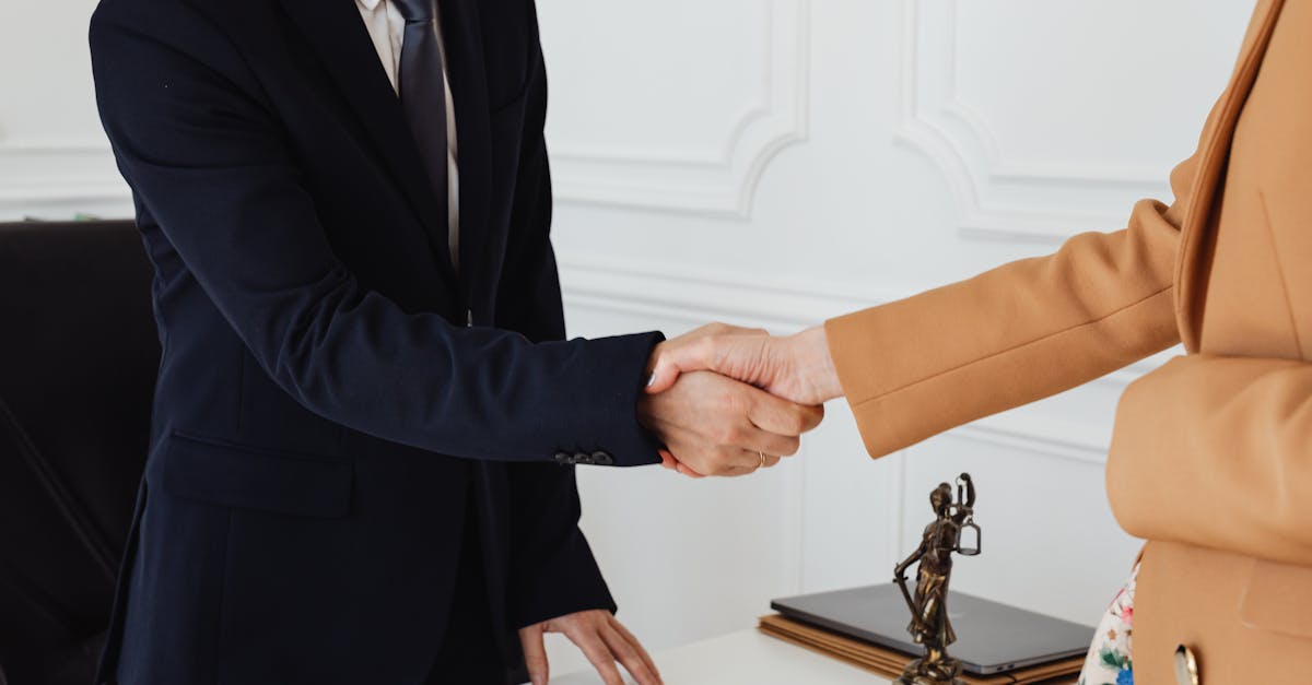 Two business professionals shaking hands in an office, showcasing agreement.