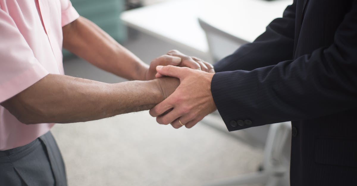Close-up of a formal handshake between two businessmen in an office environment.