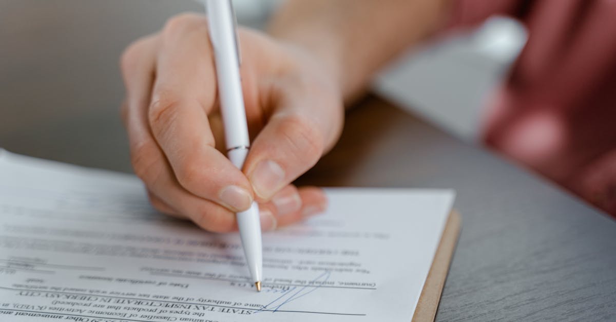 Detailed view of a hand writing a signature on an official document with a ballpoint pen.