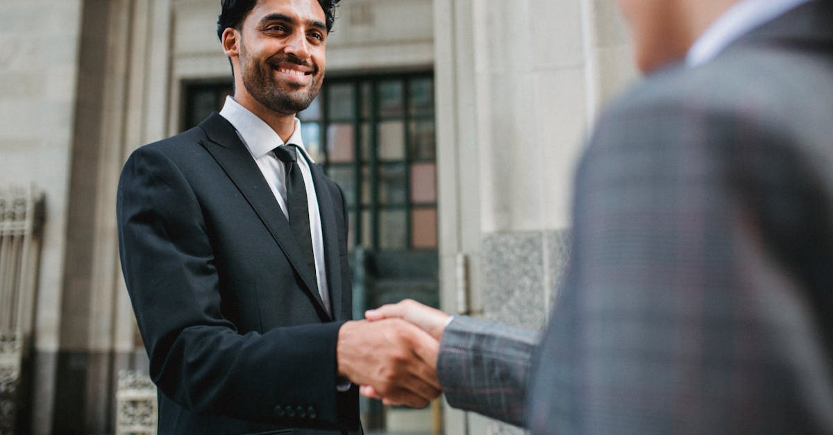 Two business professionals shake hands confidently in an urban setting.
