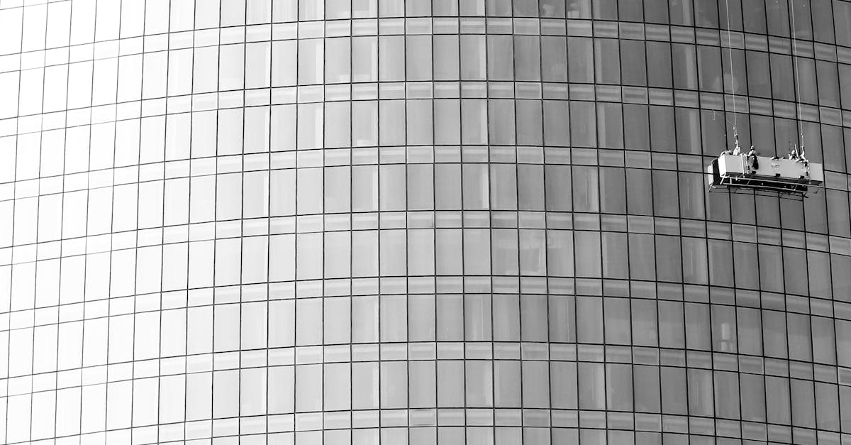 High-rise glass facade with suspended platform for window cleaning.