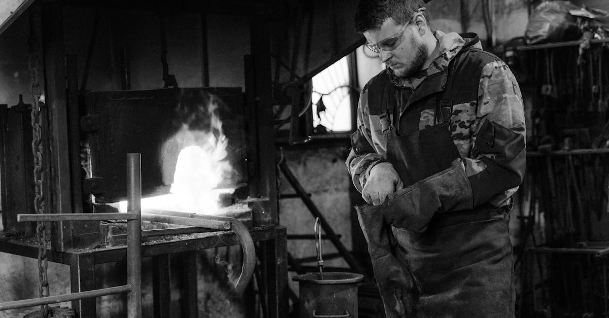 A blacksmith working in a forge, crafting metal in a monochrome industrial setting.