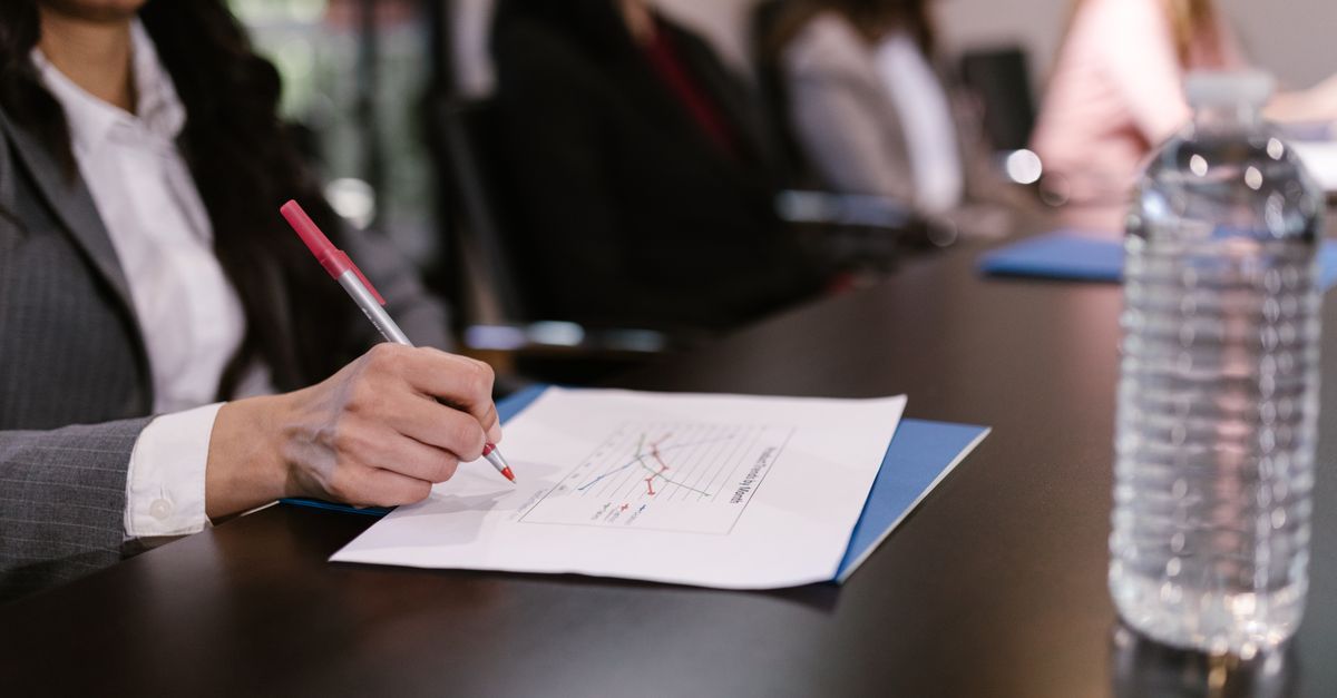 Professional business meeting with a focus on document review and graph analysis at a conference table.