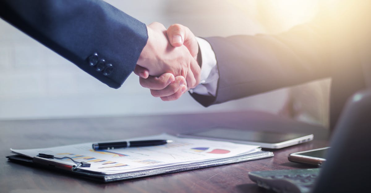 Professional handshake agreement over business charts in an office setting.