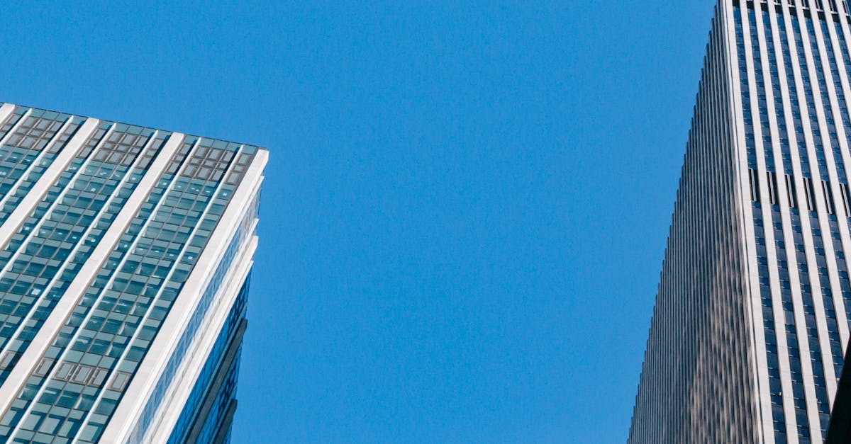 From below of modern business centers under bright blue cloudless sky in daytime