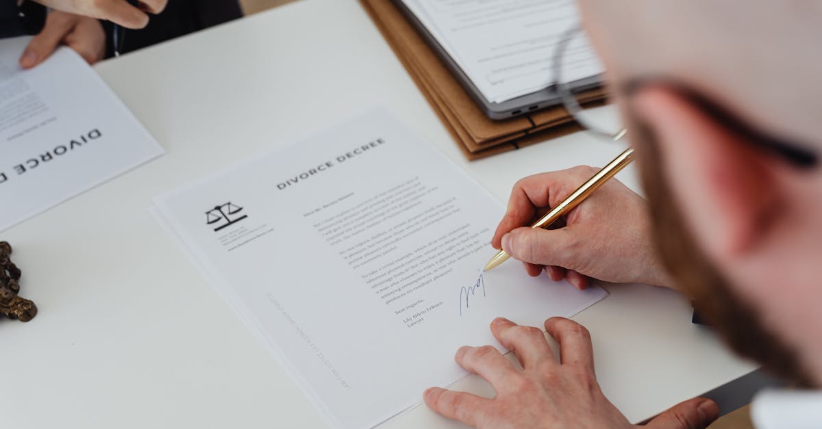 Close-up of a person signing a divorce decree on a desk.