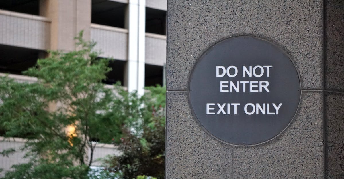A 'Do Not Enter' sign on a concrete wall outside a building with greenery.