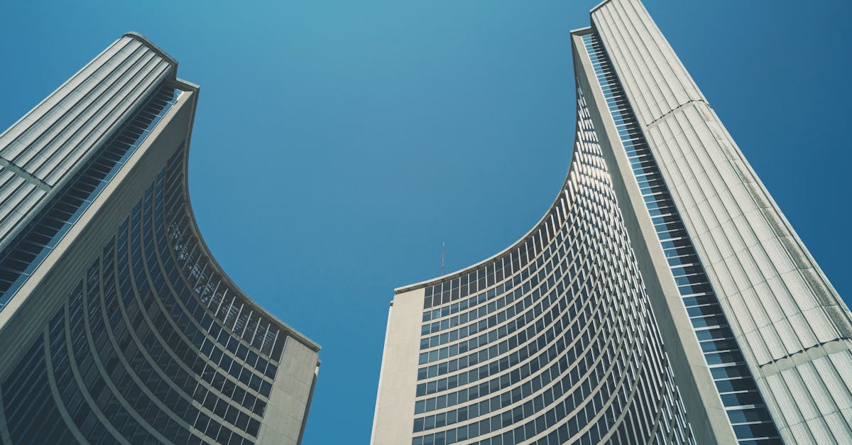 Striking architectural shot of Toronto City Hall's iconic curved buildings against a clear blue sky.