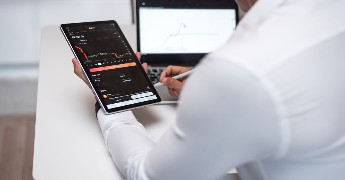 Businessman analyzing financial charts on tablet and laptop in modern office.