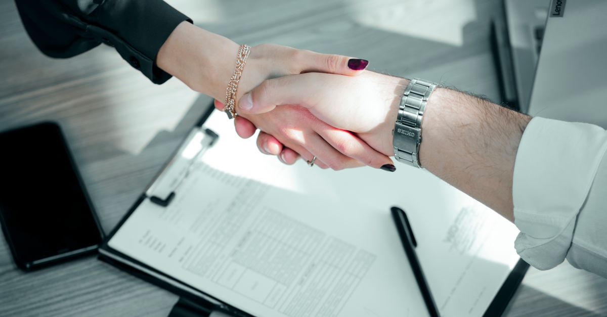 Close-up of a professional handshake over a contract, symbolizing a successful business deal.