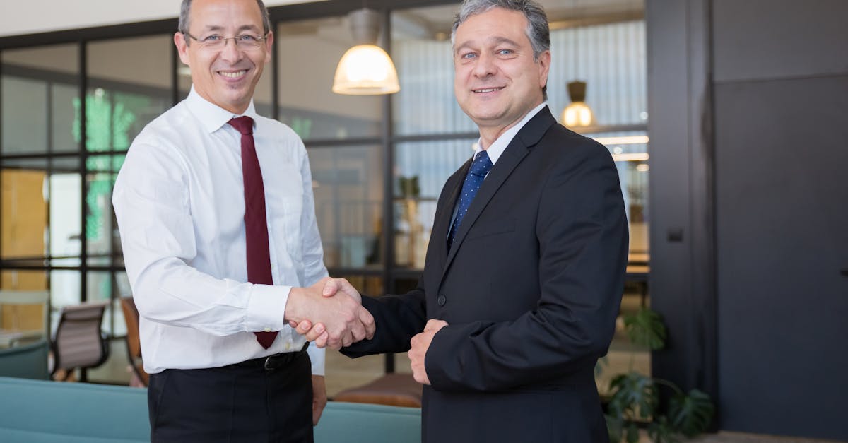 Two businessmen shaking hands in a modern office, symbolizing partnership and cooperation.