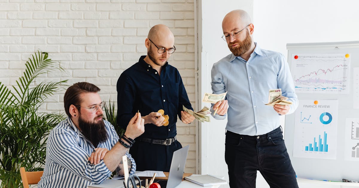 Three business colleagues discussing financial strategies and reviewing charts in a modern office.
