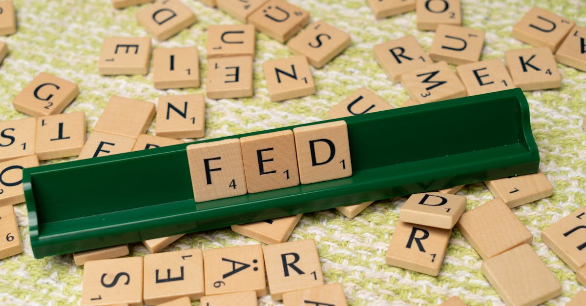 Scrabble tiles spelling 'FED' on a green rack surrounded by scattered tiles on a textured surface.