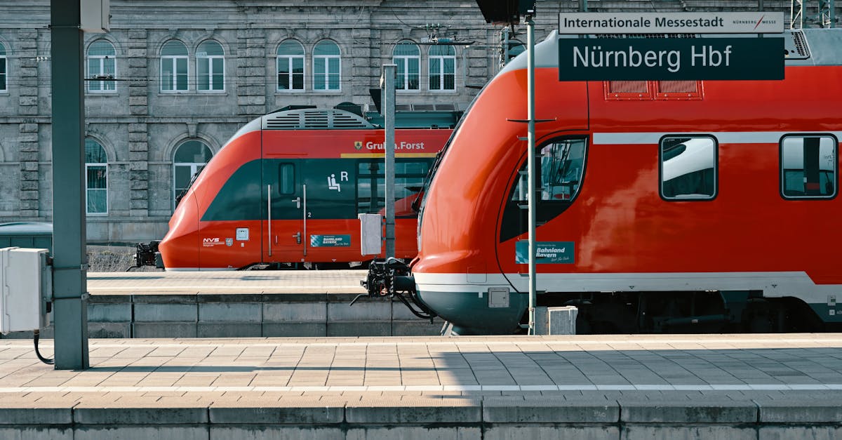 Red trains at Nürnberg Hauptbahnhof station on a sunny day, showcasing public transportation.