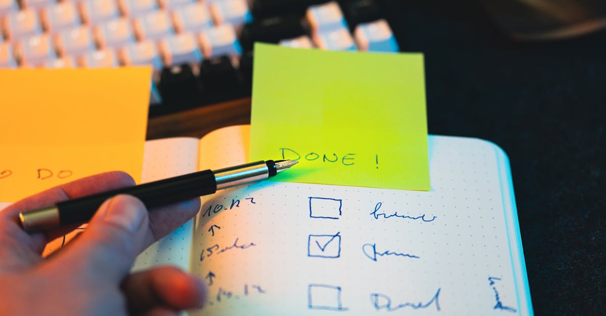 Close-up of hand holding pen over notebook checklist with sticky notes labeled 'DONE!'