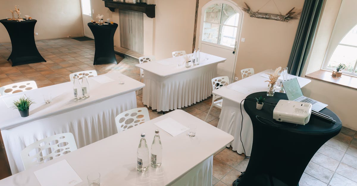 Spacious meeting room with classy linen-covered tables, chairs, and a projector ready for presentations.
