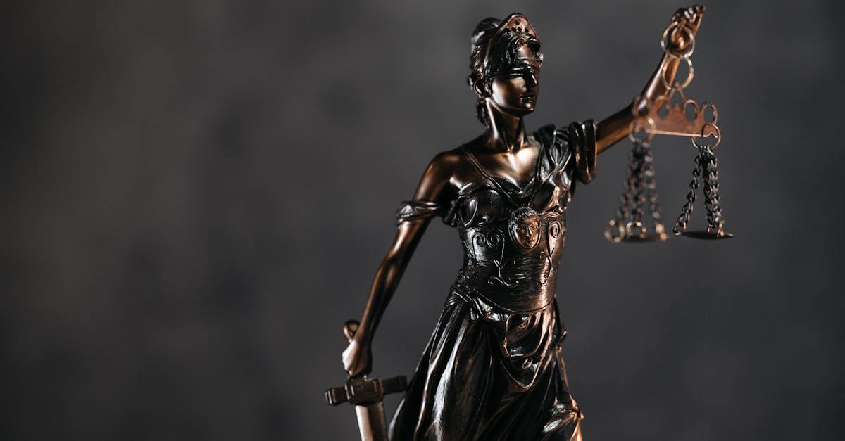 Detailed bronze Lady Justice statue with scales and sword against a dark background, symbolizing law and justice.