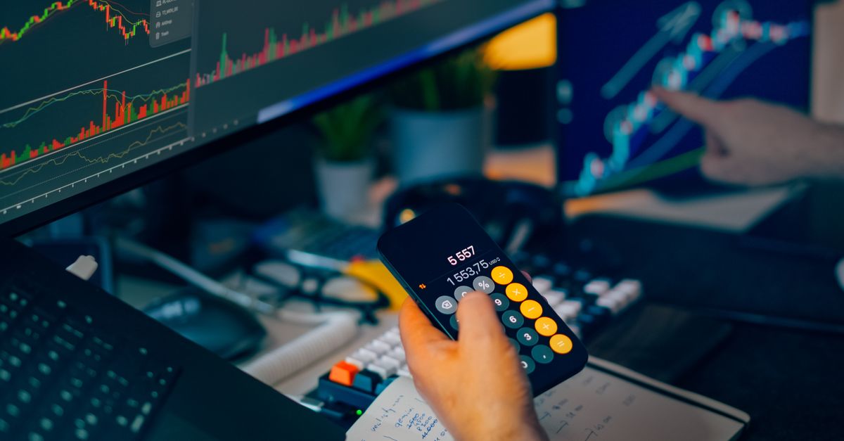 A focused shot of financial trading with screens, calculator, and data charts.