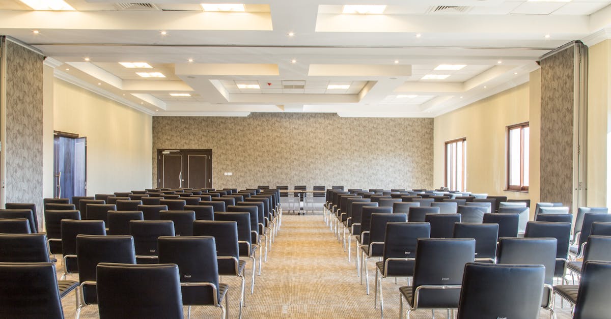 Spacious empty conference room with modern design and neatly arranged black chairs.