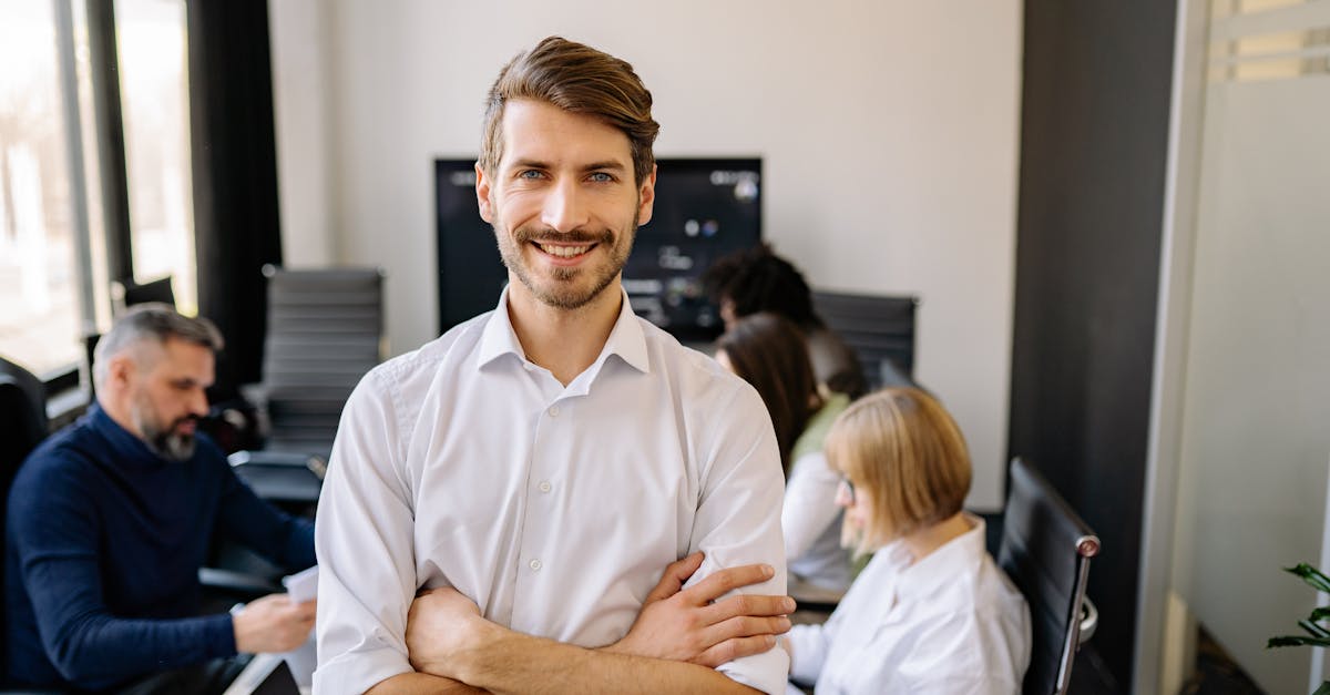 Smiling businessman standing confidently with arms crossed in an office setting.