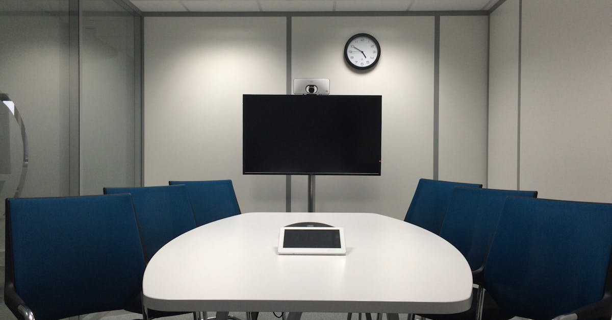 Sleek conference room with a table, chairs, TV, and video conferencing equipment.