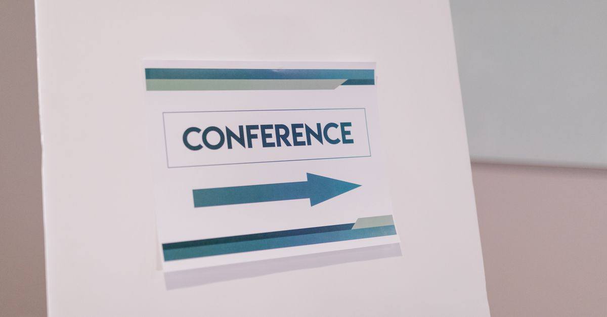 Close-up of a conference directional sign indoors, guiding participants.