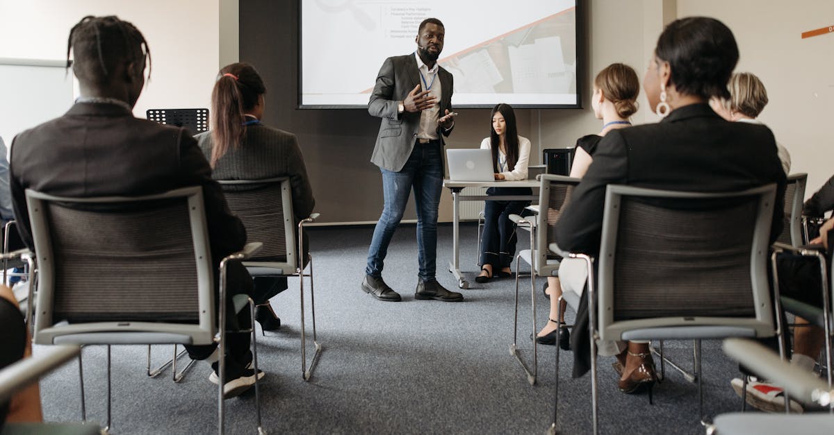 Diverse group attending a business seminar with a presenter and screen display.