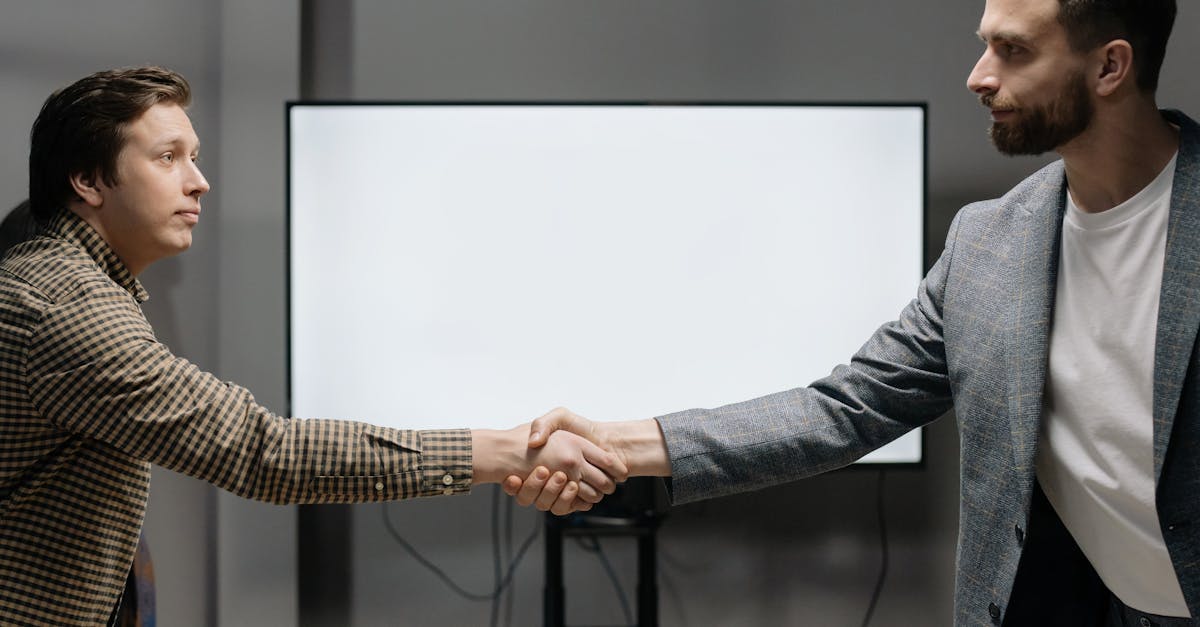 Two businessmen shake hands in an office setting, signifying agreement and cooperation.