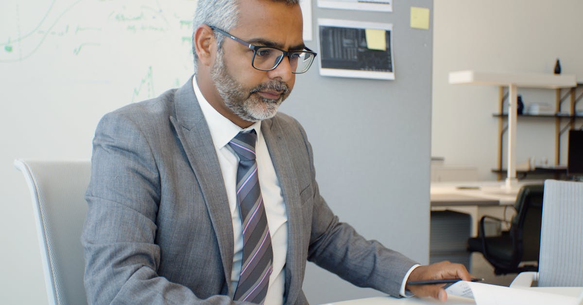 Asian man in corporate attire working at a desk in an office setting.