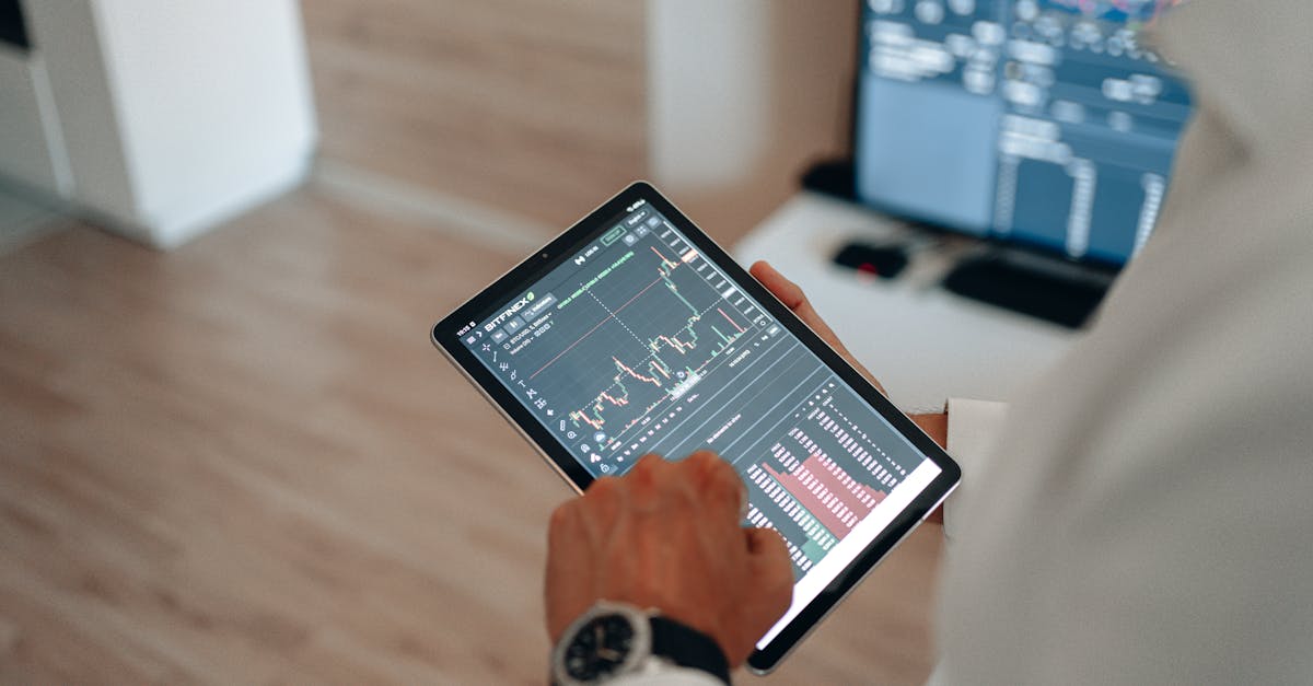 Close-up of hands using a tablet for online trading and market analysis.