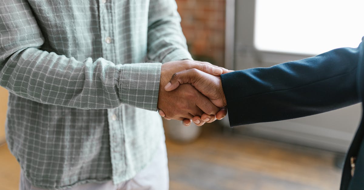 Close-up of two business professionals shaking hands in a modern office environment.