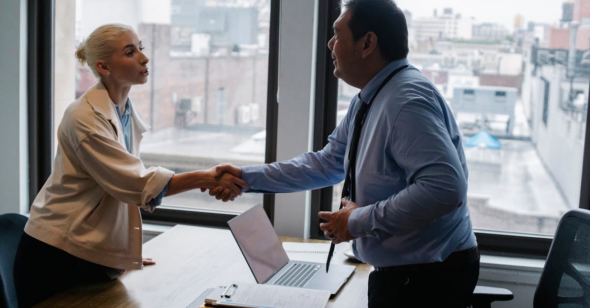 Professional handshake between two colleagues in a modern office setting.