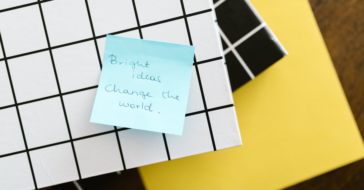 Blue sticky note with motivational quote on grid and solid colored notebooks.