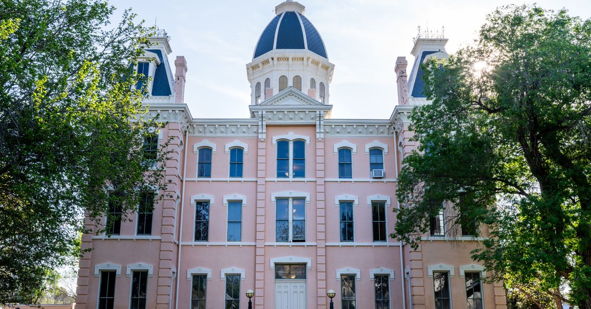 Front view of the iconic Presidio County Courthouse in Marfa, Texas, framed by trees under a clear sky.