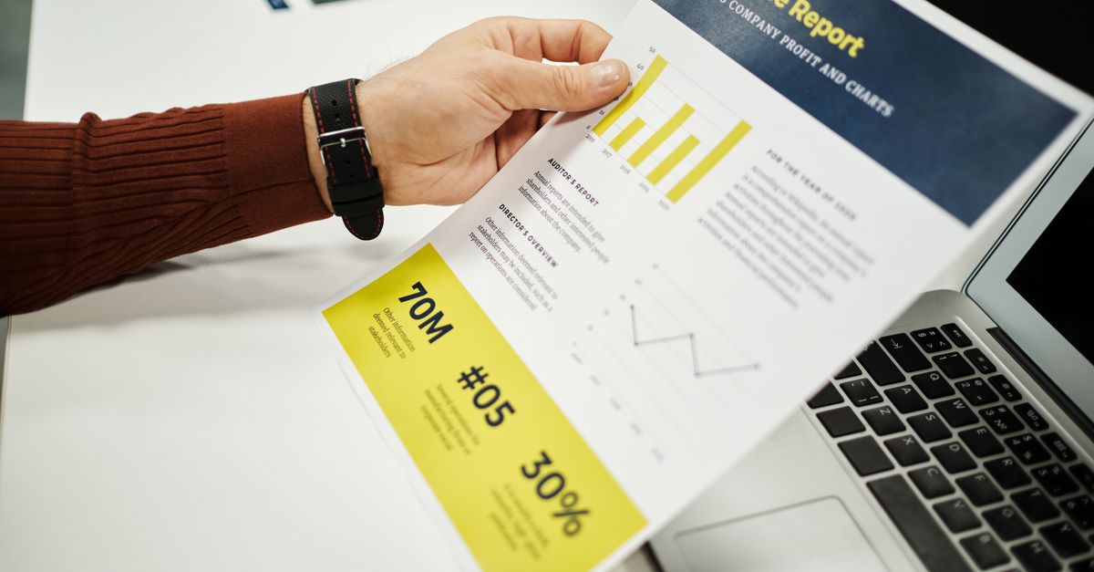 Person analyzing finance report with graphs at desk, ideal for business concepts.