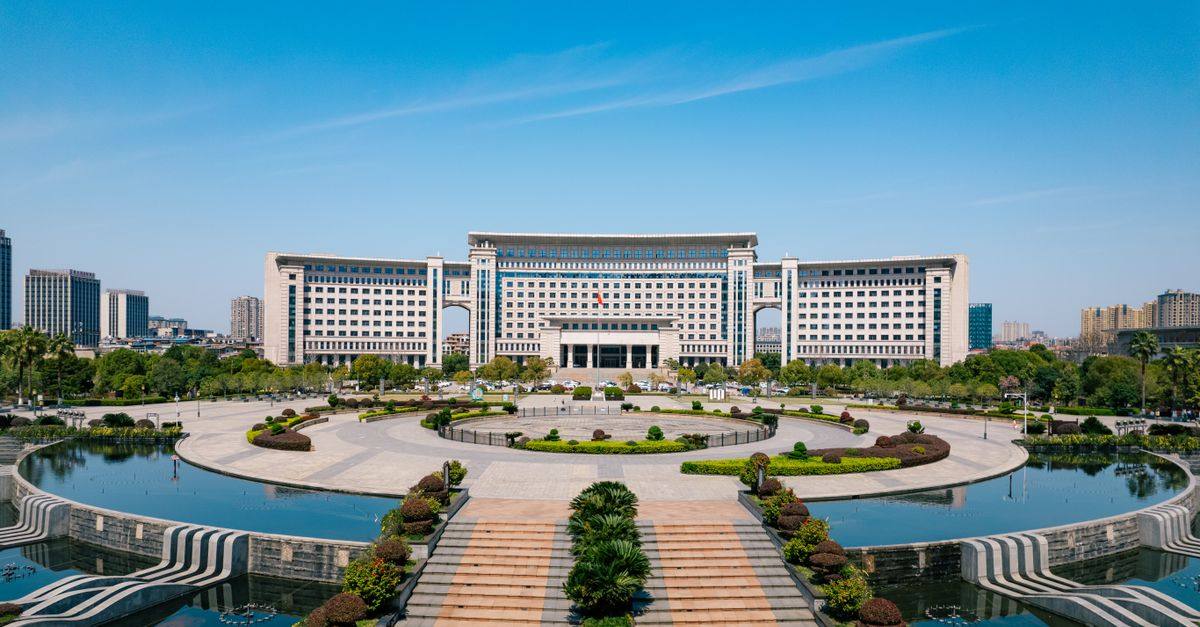Stunning architectural building with symmetrical design and a reflecting pool, set against a clear blue sky.