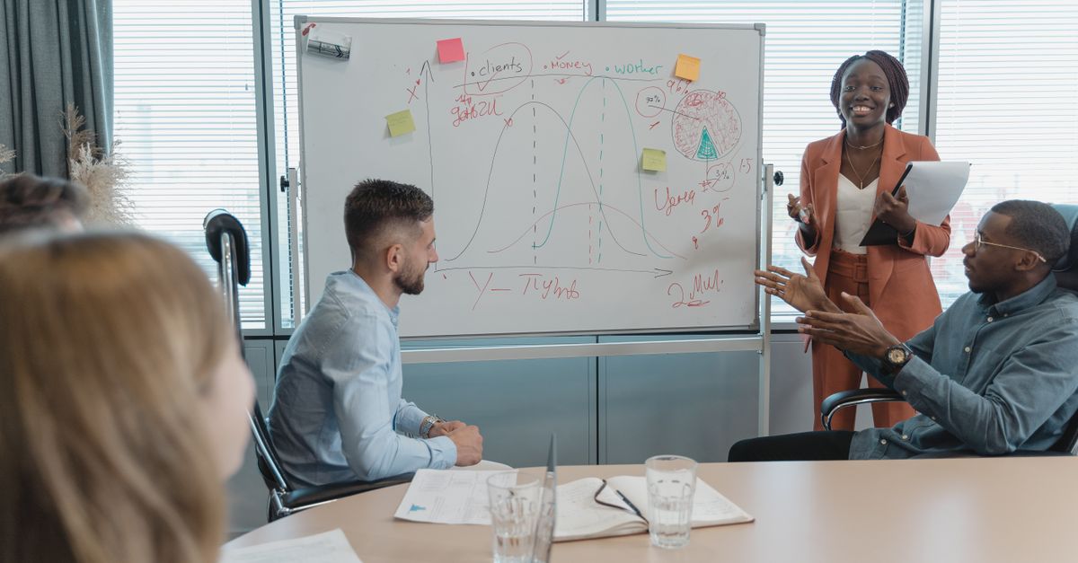 Multicultural team discussing strategies in a conference room with a whiteboard presentation.