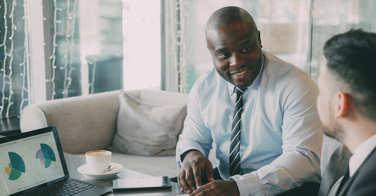 Two businessmen discussing projects over coffee and data charts.